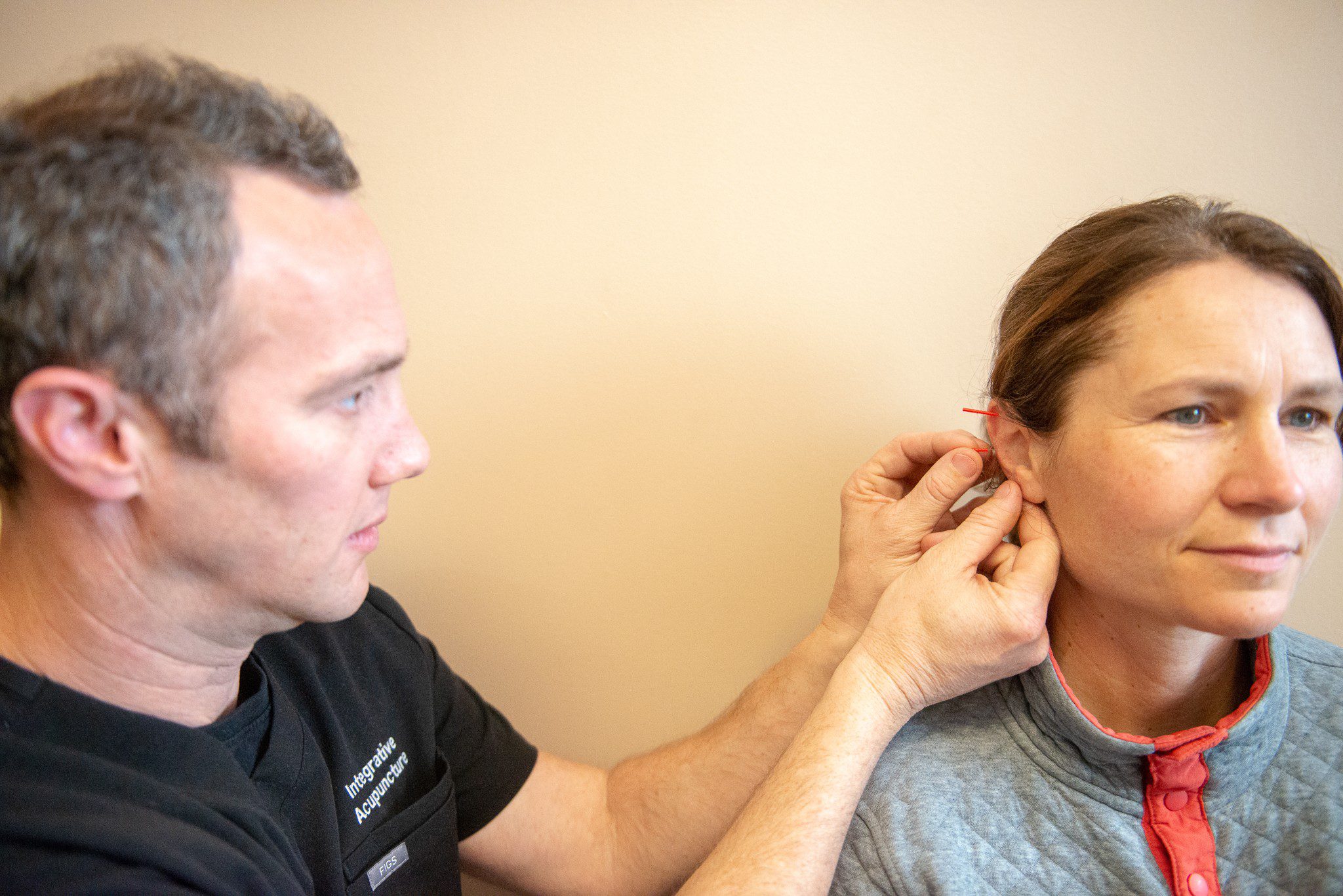 Jonathan placing acupuncture needles in patient's ear.