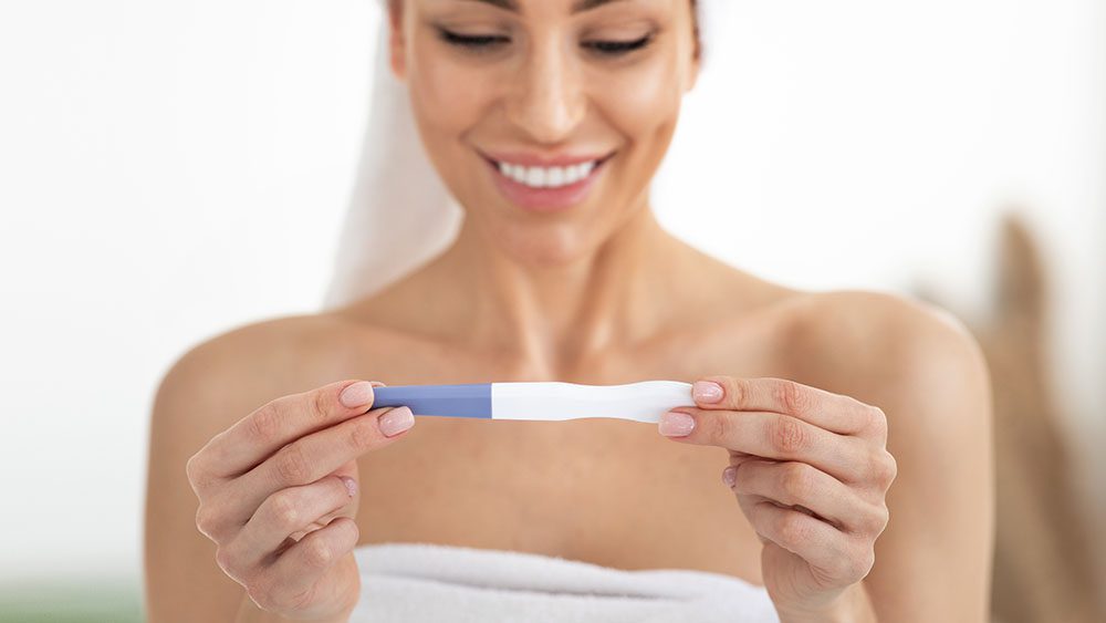 Person holding pregnancy test and smiling