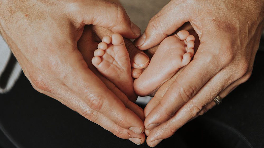 hands together in a heart shape framing a baby's feet
