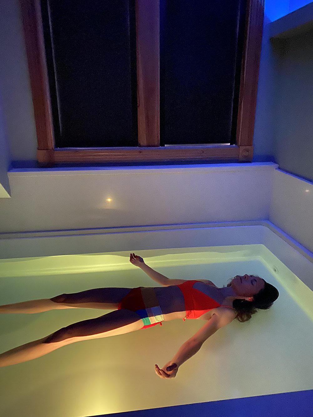 Woman floats in float tank almost in the dark. Wellness in Vermont
