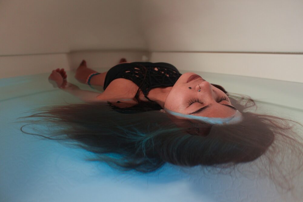 Person with eyes closed floating in sensory deprivation tank