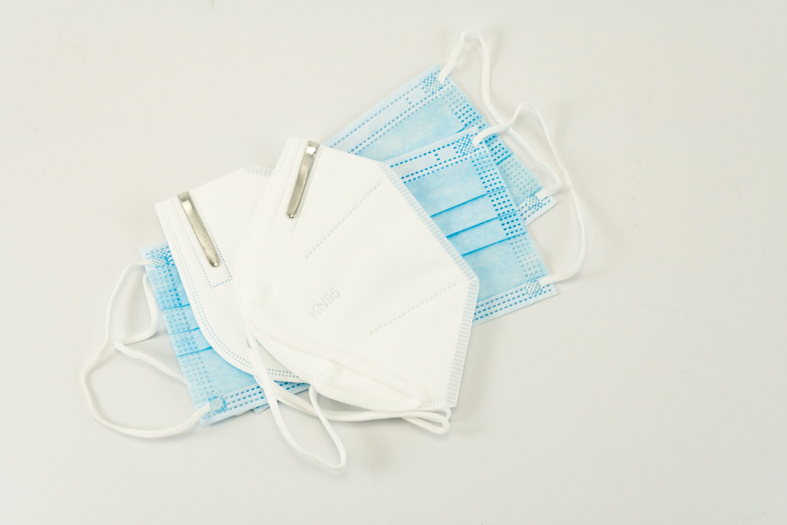 3 face masks against a white background: 2 surgical face mask and 1 N95 mask.
