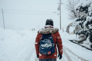 Person with back to camera walking down snow covered road in winter