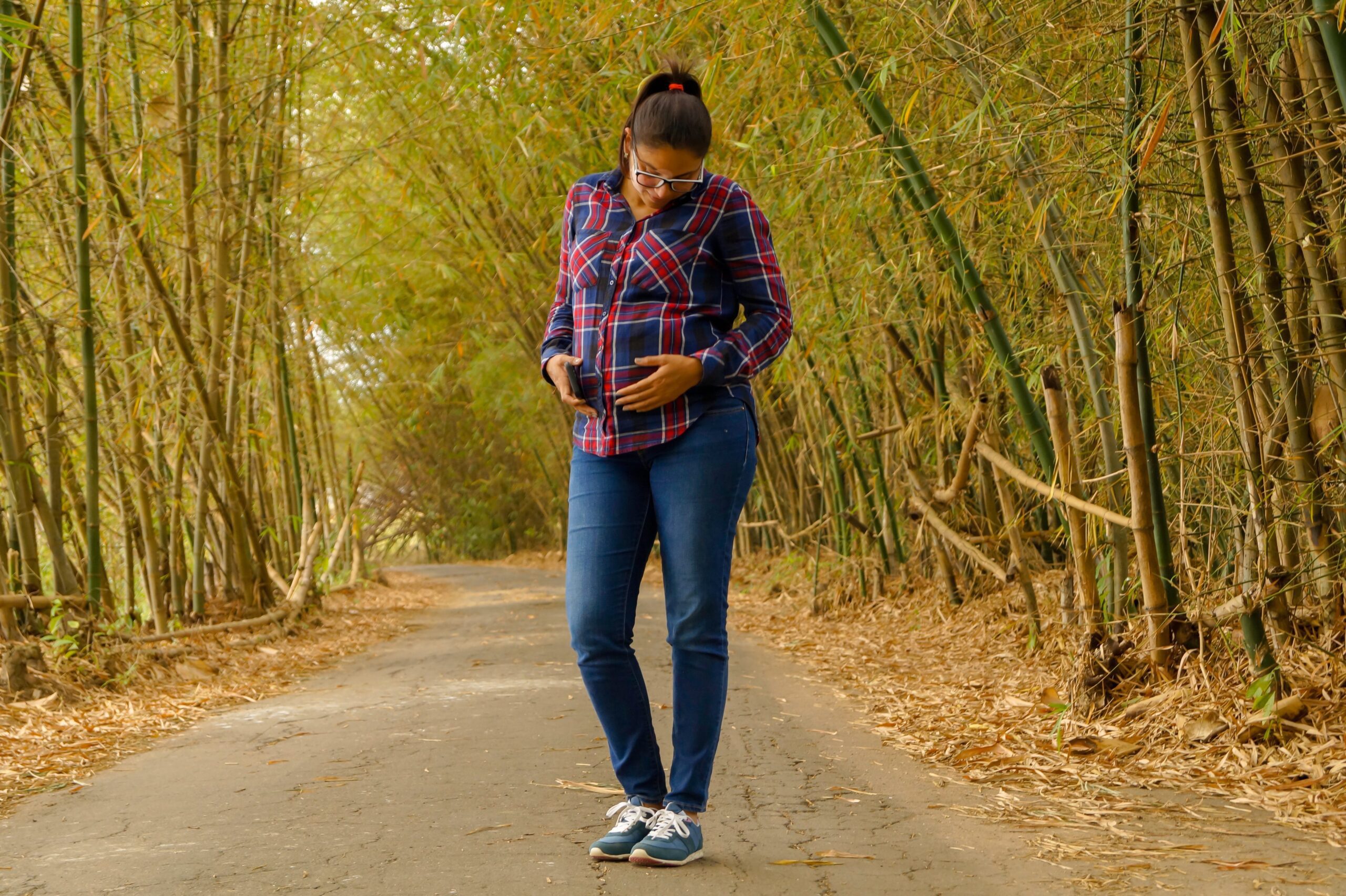 exercise in labor: person standing on dirt road through a bamboo forest while pregnant