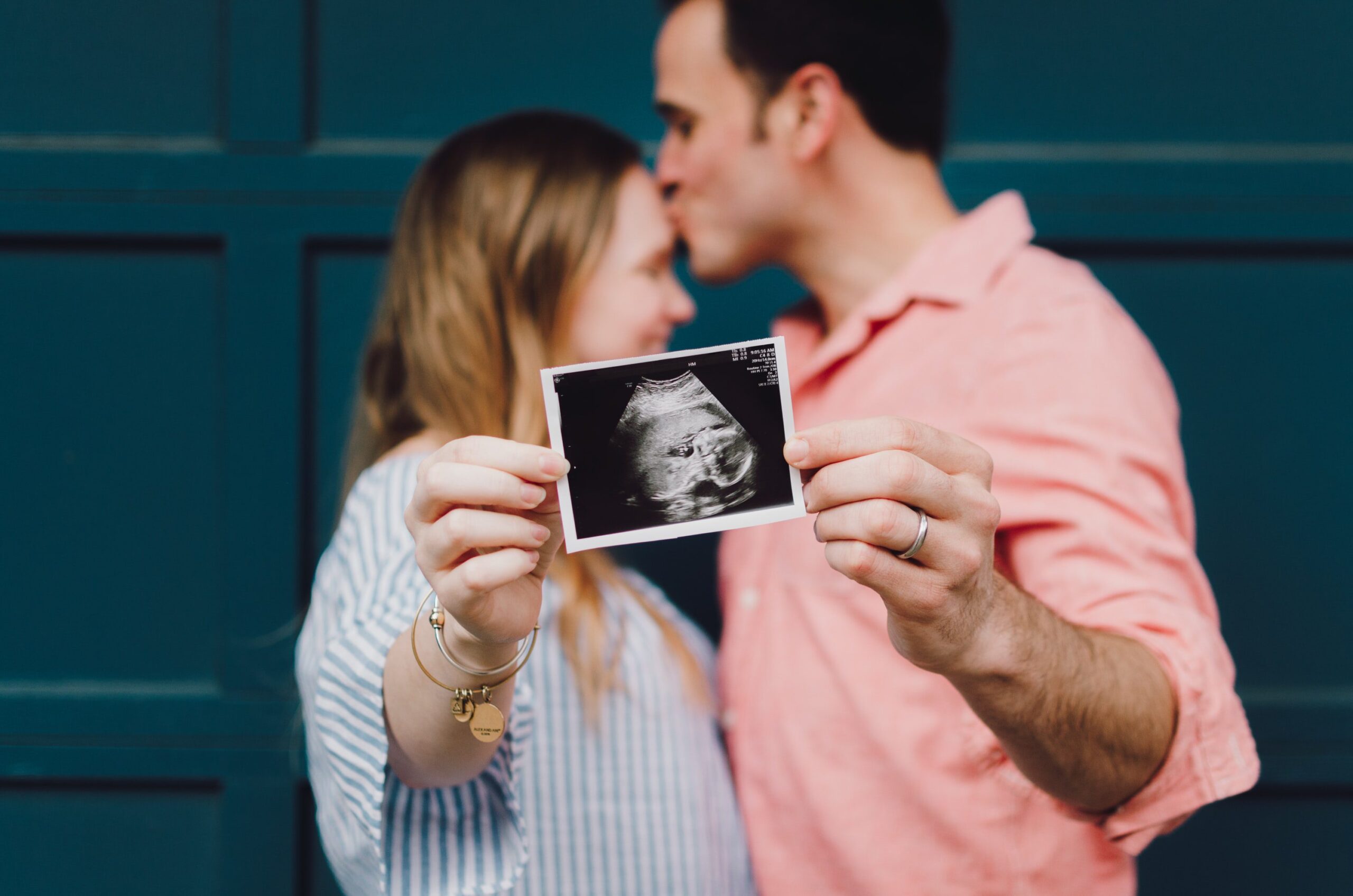 Couple holding photo of ultrasound to camera. morning sickness