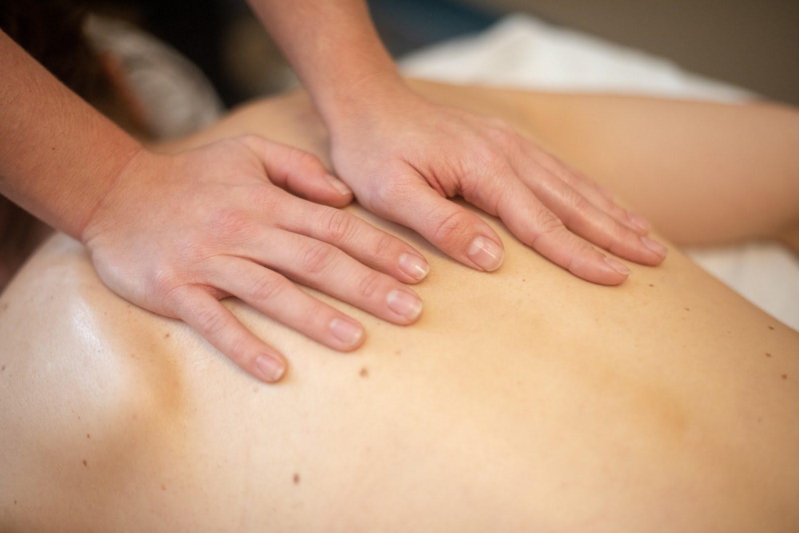 Massage therapy: masseuse has hands on patient's back