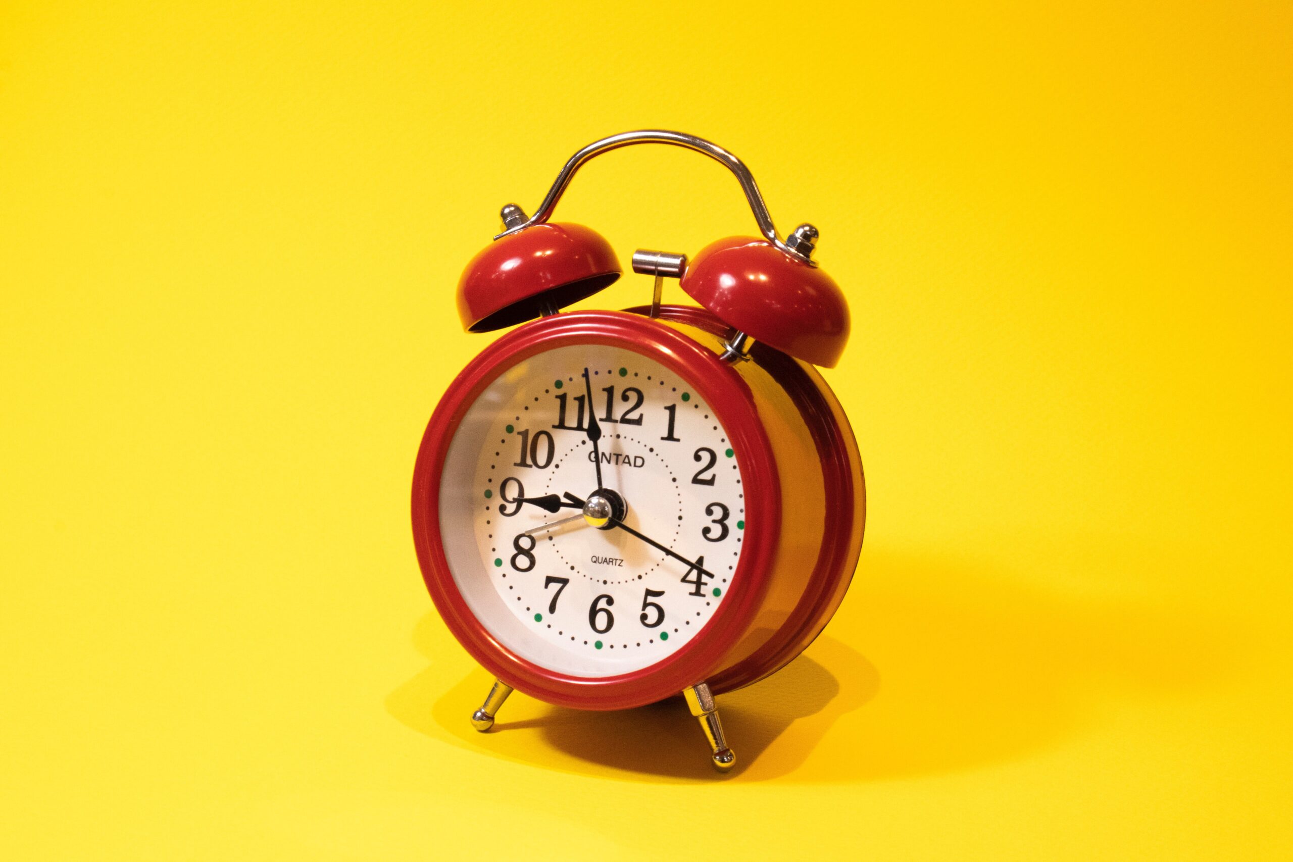 red alarm clock against bright yellow background
