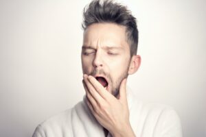 Person yawning with hand covering mouth.