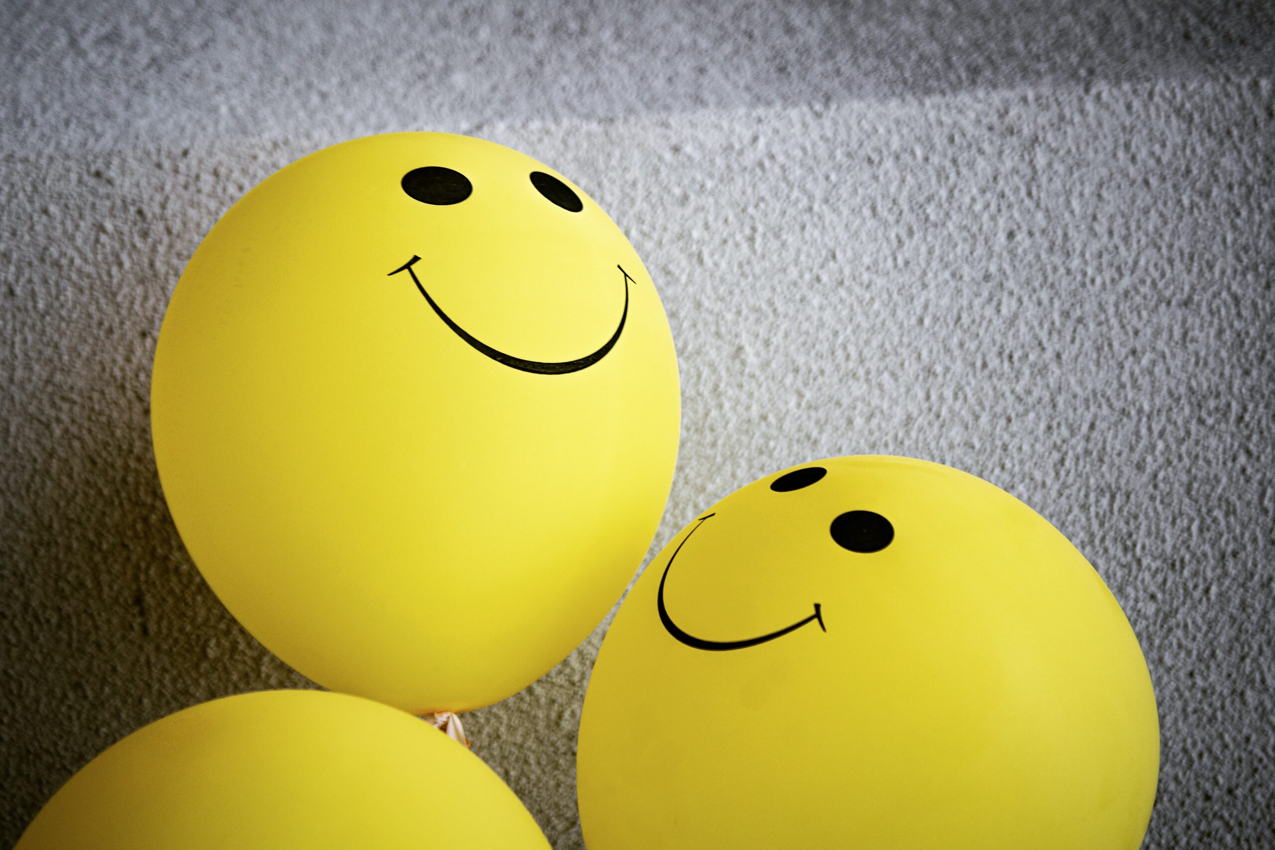 3 yellow balloons with smiley faces on them