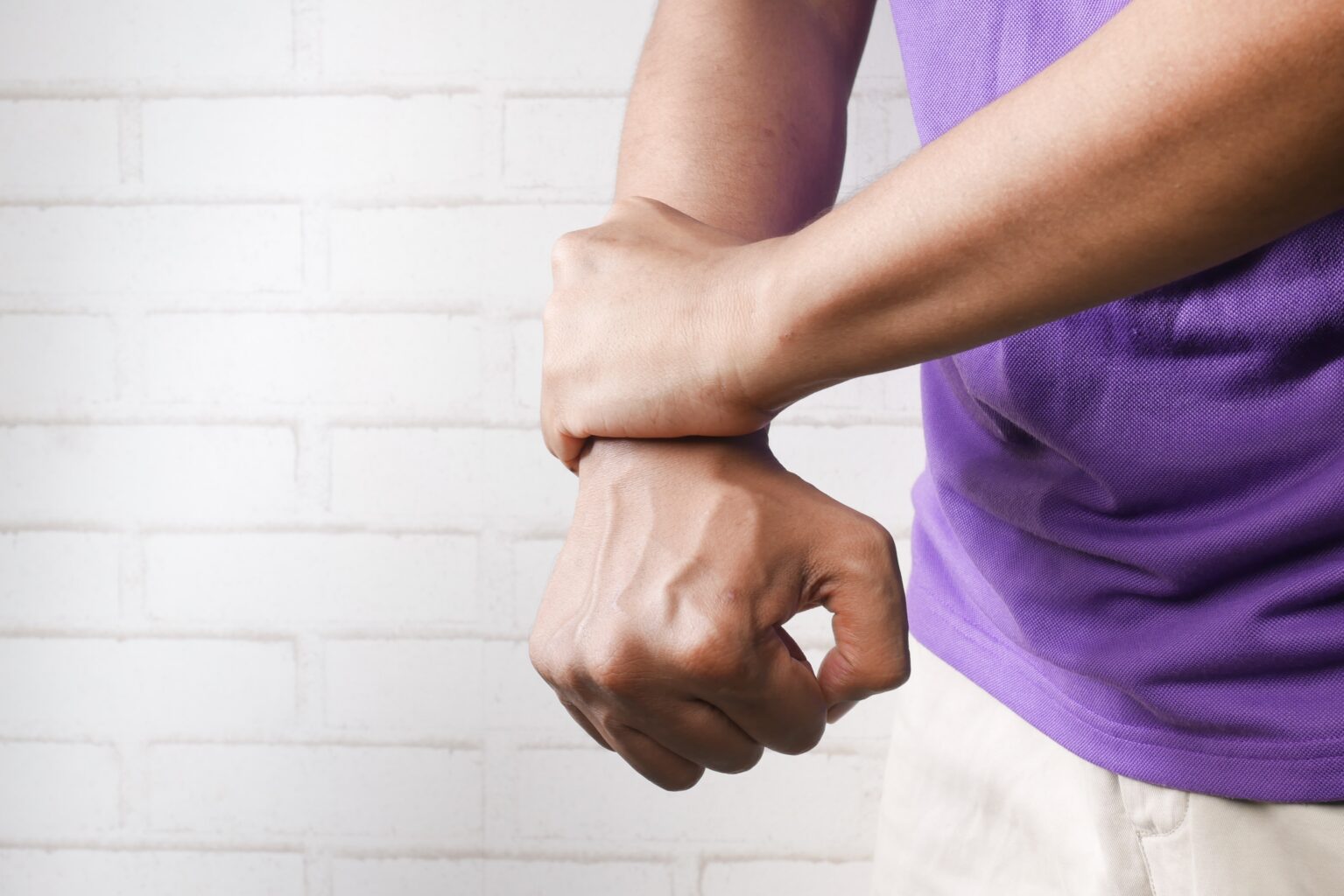 Person holding their other wrist in pain while fist is clenched